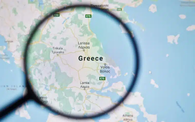 Map of Greece viewed through a magnifying glass, emphasizing the country on the surrounding map.